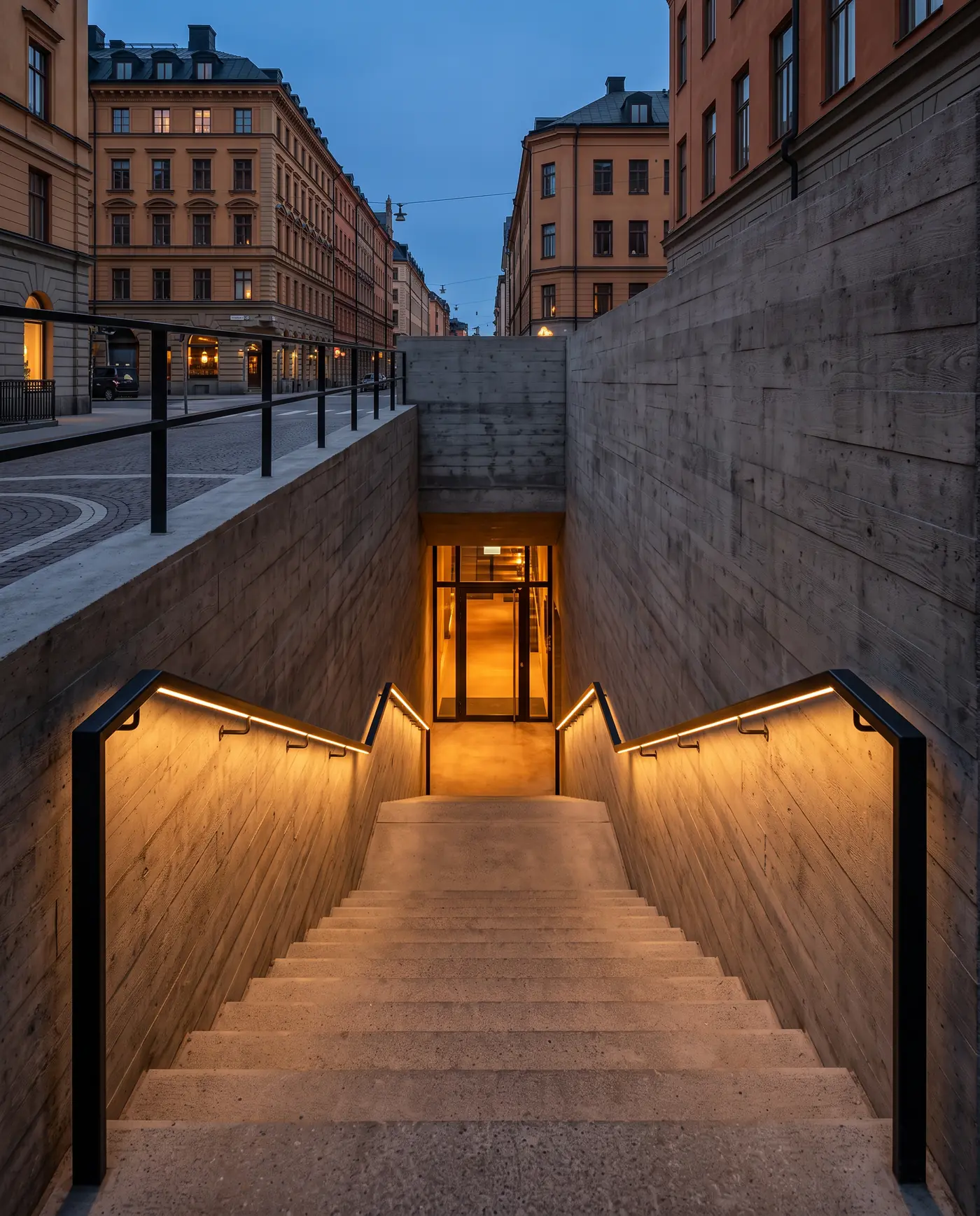 Konceptbild av en betongtrappa som leder från en Stockholmsgata ned till en varmt upplyst entré.